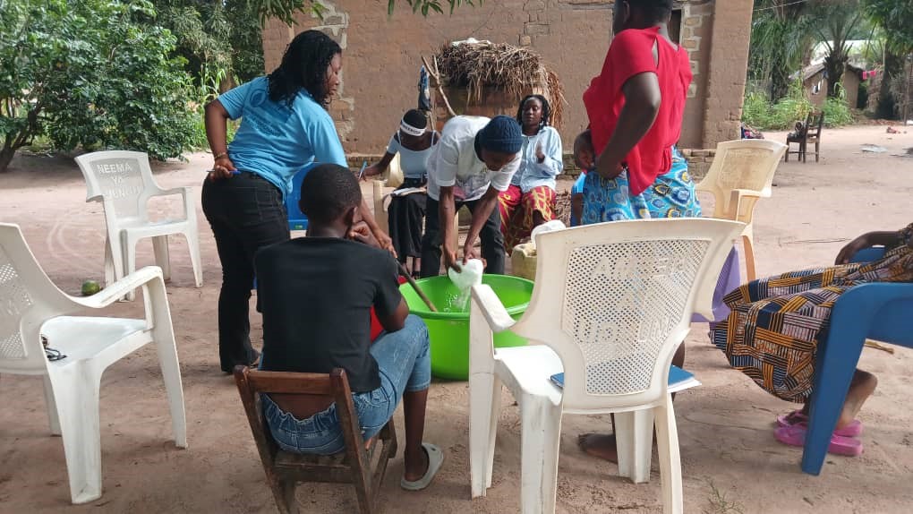 Séance de travail entre les associations de filles Fabrication et Production: Action des filles mélangeant la pâte à savon ou pétrissant la farine et le facilitateur de DEDI/Manono